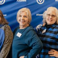 Four event guests taking photo together in front of GVSU backdrop